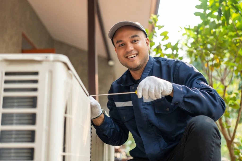 Ac Installation A man wearing a blue shirt and white gloves repairs an air conditioner, demonstrating technical skill and attention to detail.